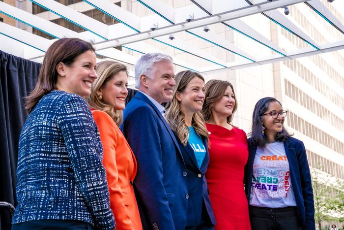 Group of professionally dressed attendees smiling together at a corporate event outdoors.