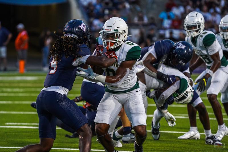 An American football player in a green and white uniform holding the ball during a game.
