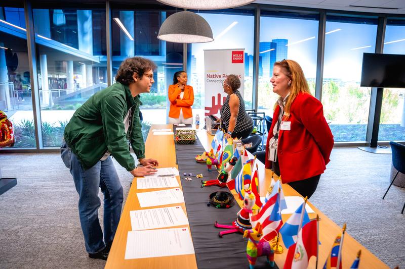 Attendees gather around a sign-in table with cultural decorations at a Wells Fargo corporate event.