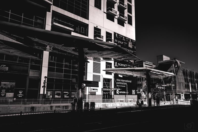 Black and white shot of a modern urban downtown building with digital billboards and street signage.