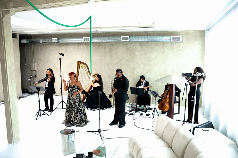 A musical ensemble with a saxophonist, harpist, and guitarist performing indoors.