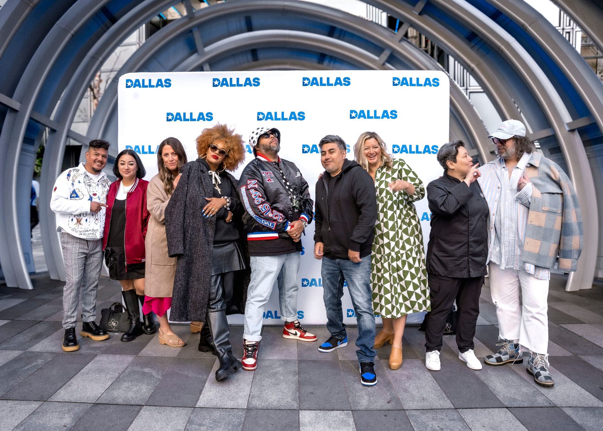 Four people pose for a photo in front of a Dallas branded step-and-repeat banner.
