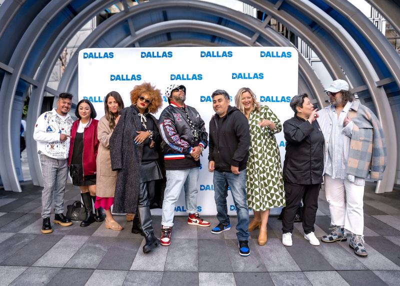Four people pose for a photo in front of a Dallas branded step-and-repeat banner.