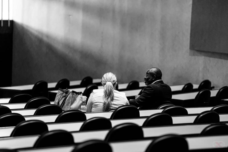 Black and white photo of audience members seated in tiered rows during a conference or seminar.