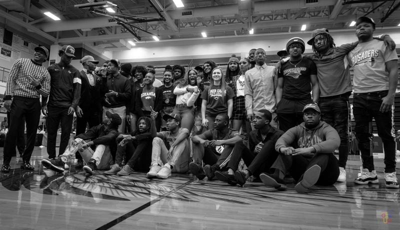 Black and white group photograph of student athletes posing together on a gymnasium basketball court.